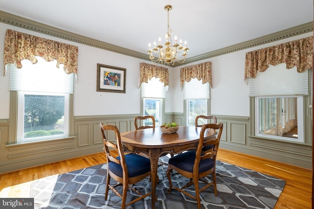 dining space with a notable chandelier, wood finished floors, and wainscoting