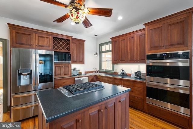 kitchen with dark countertops, a kitchen island, appliances with stainless steel finishes, and a sink