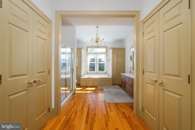 bathroom with vanity, wood finished floors, a shower stall, a garden tub, and a chandelier