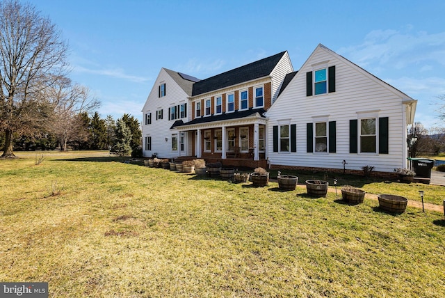 rear view of house featuring a yard and solar panels