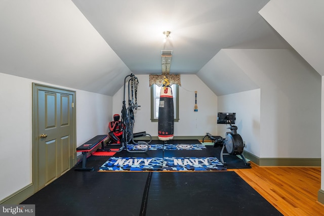 exercise room with vaulted ceiling, baseboards, and wood finished floors