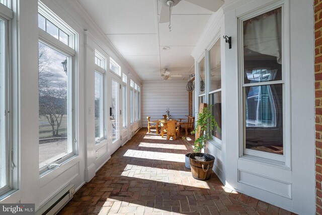 sunroom featuring baseboard heating, a healthy amount of sunlight, and a ceiling fan