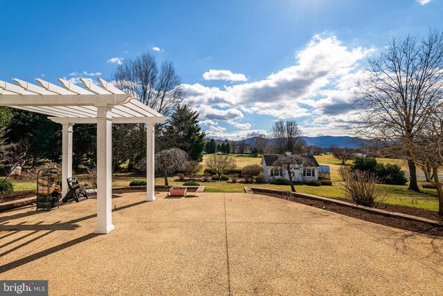 view of patio / terrace with a mountain view, an outbuilding, and a pergola