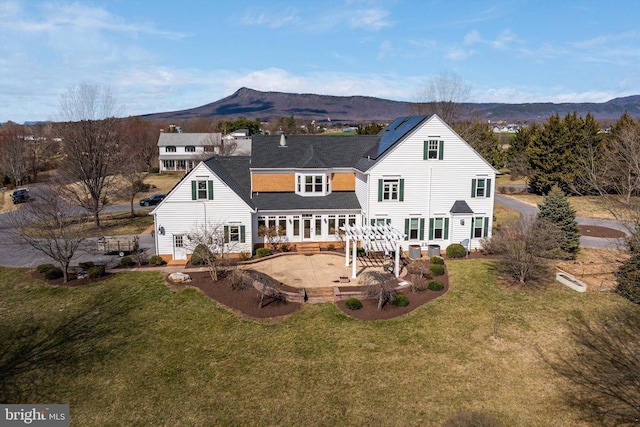 rear view of house with a patio, a yard, and a deck with mountain view