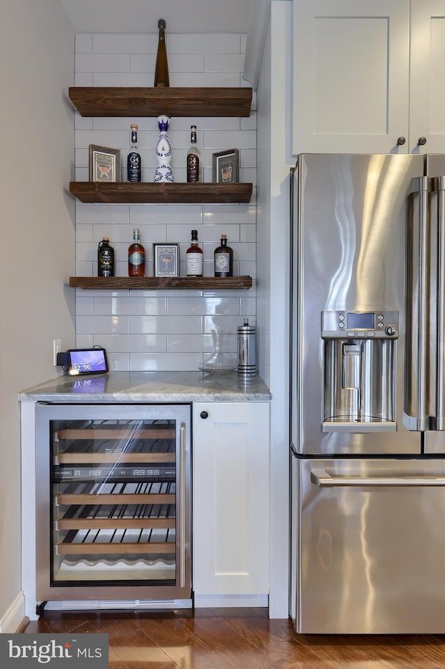 bar featuring wine cooler, backsplash, a dry bar, and stainless steel fridge with ice dispenser