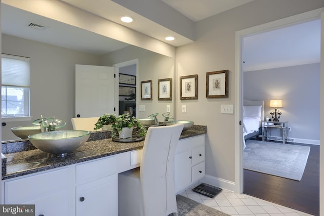 ensuite bathroom with tile patterned flooring, visible vents, connected bathroom, baseboards, and vanity