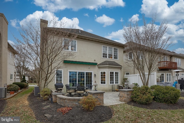 back of property with a patio area, stucco siding, central AC, and fence