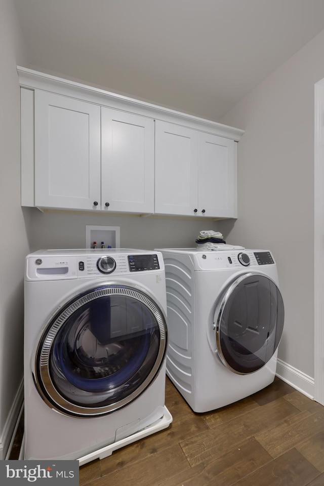 clothes washing area with cabinet space, independent washer and dryer, dark wood-style flooring, and baseboards