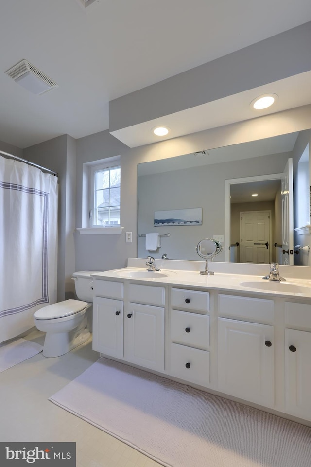 full bathroom featuring double vanity, toilet, visible vents, and a sink