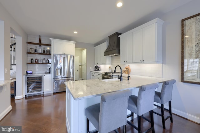 kitchen featuring high quality appliances, custom range hood, a sink, wine cooler, and light stone countertops