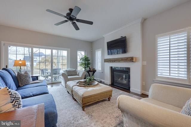 living room featuring wood finished floors, baseboards, a large fireplace, and ceiling fan