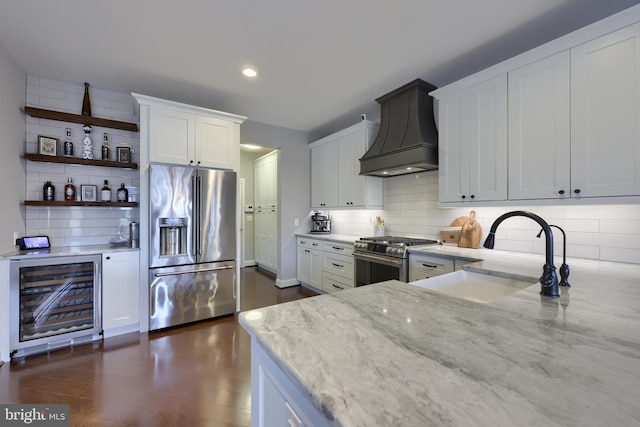 kitchen featuring premium range hood, high quality appliances, light stone counters, a sink, and wine cooler