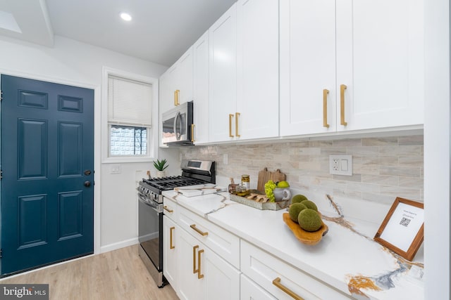 kitchen featuring backsplash, baseboards, light wood-type flooring, white cabinets, and stainless steel appliances