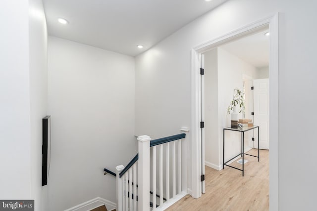 hall with recessed lighting, baseboards, an upstairs landing, and wood finished floors