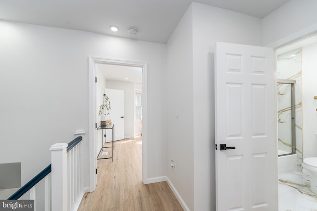 hall with baseboards, an upstairs landing, and light wood-style flooring