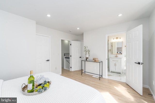 bedroom with connected bathroom, baseboards, recessed lighting, light wood-style floors, and a sink