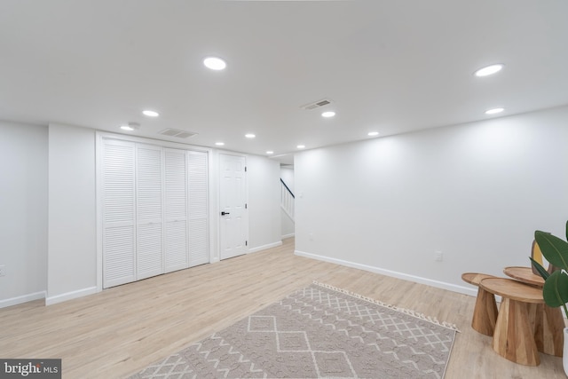 finished basement with recessed lighting, visible vents, and wood finished floors