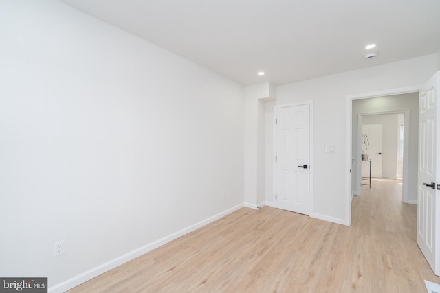 spare room with light wood finished floors, recessed lighting, and baseboards