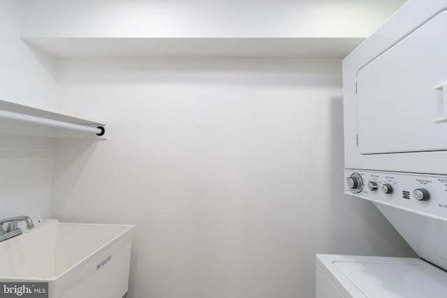 clothes washing area with stacked washer / dryer, laundry area, and a sink