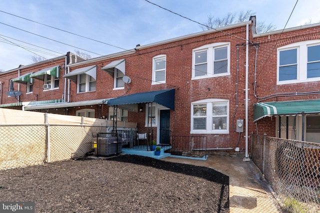 back of property with brick siding, cooling unit, and fence