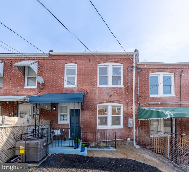 rear view of house featuring cooling unit, brick siding, and fence