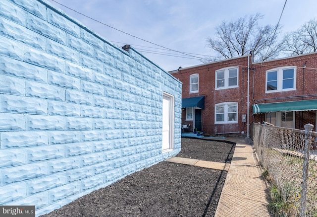 back of house featuring brick siding and fence