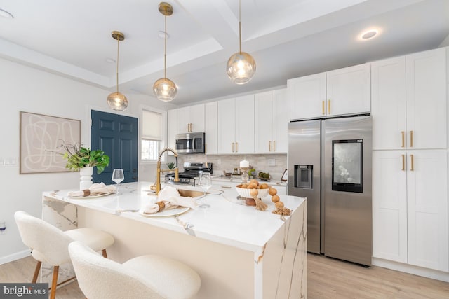 kitchen featuring a tray ceiling, stainless steel appliances, and white cabinetry