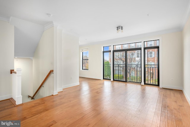 empty room with ornamental molding, baseboards, and wood finished floors