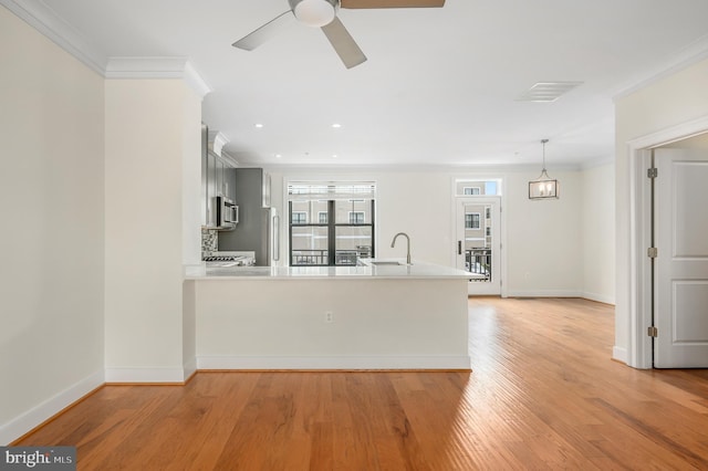 kitchen with visible vents, a peninsula, stainless steel microwave, and light countertops