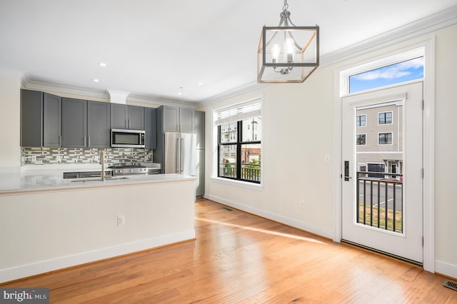 kitchen with tasteful backsplash, light wood-style flooring, appliances with stainless steel finishes, and crown molding