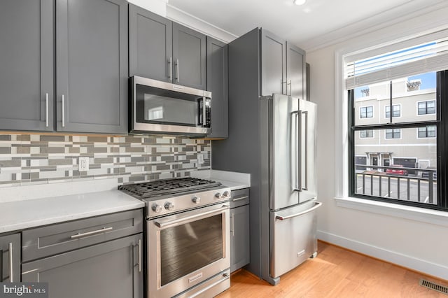 kitchen featuring tasteful backsplash, visible vents, light wood-type flooring, gray cabinets, and stainless steel appliances