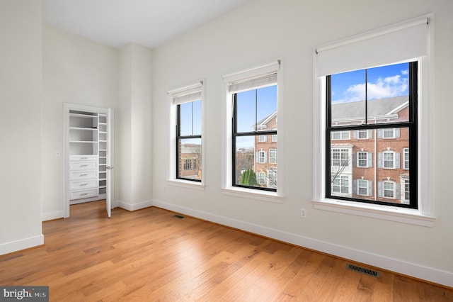 spare room with light wood-style floors, visible vents, and baseboards