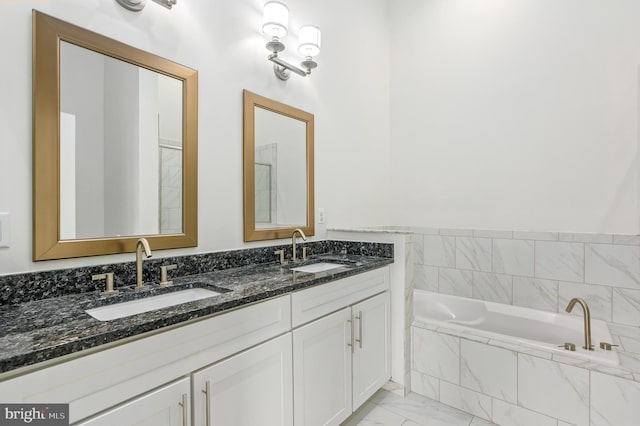 full bath with a sink, marble finish floor, a bath, and double vanity