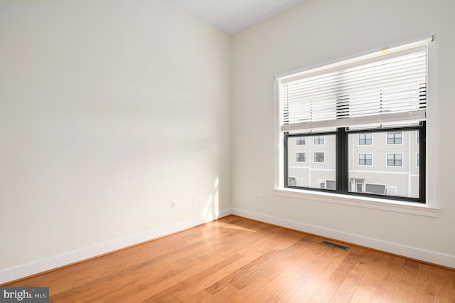 spare room featuring visible vents, baseboards, and wood finished floors