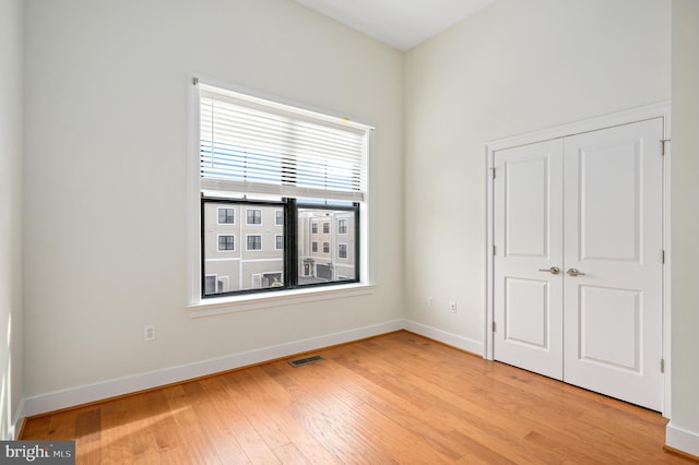 unfurnished bedroom featuring a closet, visible vents, light wood-style flooring, and baseboards