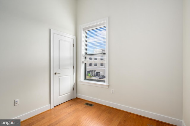 spare room with light wood-style floors, visible vents, and baseboards