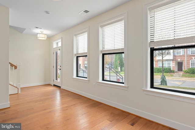 foyer featuring light wood-type flooring, visible vents, baseboards, and stairs