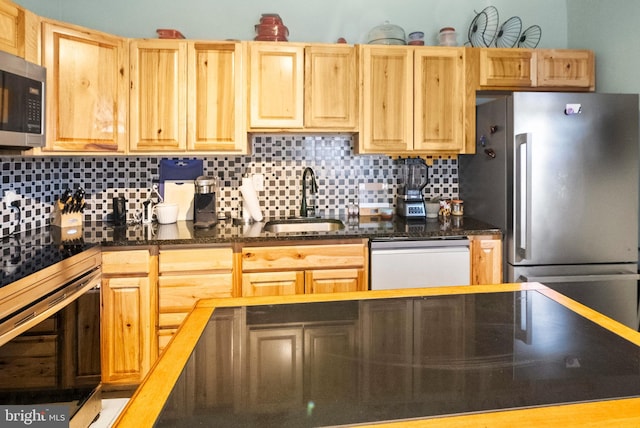 kitchen with a sink, decorative backsplash, appliances with stainless steel finishes, and light brown cabinetry