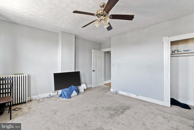 unfurnished bedroom featuring a textured ceiling, baseboards, radiator, and carpet