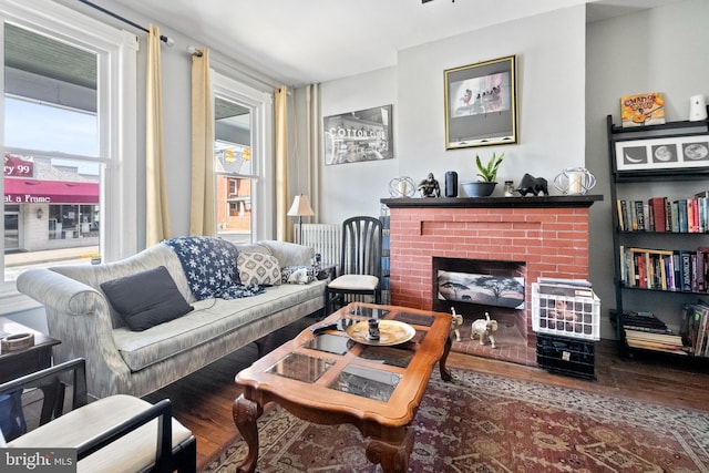 living room featuring a brick fireplace and wood finished floors