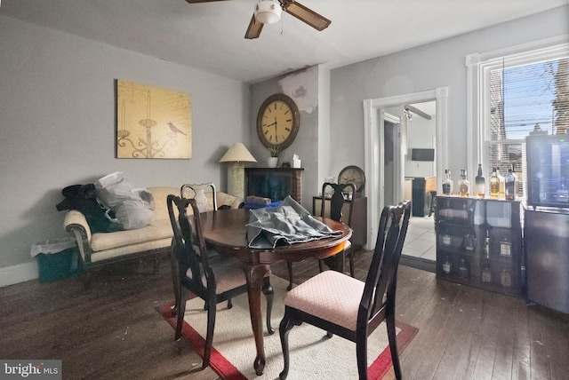 dining area with a ceiling fan, baseboards, and wood-type flooring