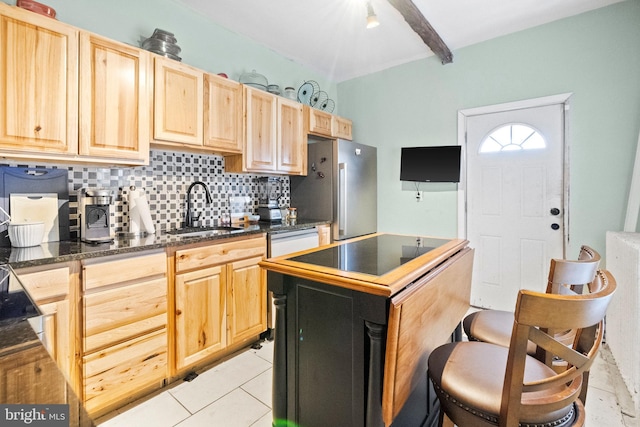 kitchen featuring dark countertops, light brown cabinets, backsplash, and a sink