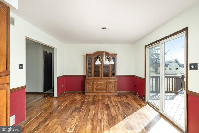 dining area featuring visible vents, an inviting chandelier, wood finished floors, and wainscoting