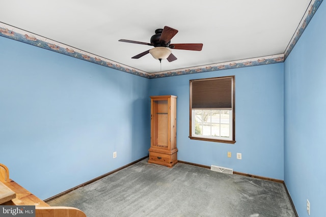 carpeted spare room with visible vents, baseboards, and a ceiling fan