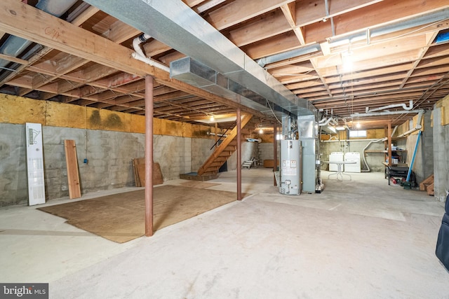 unfinished below grade area featuring gas water heater, stairway, and washer and clothes dryer