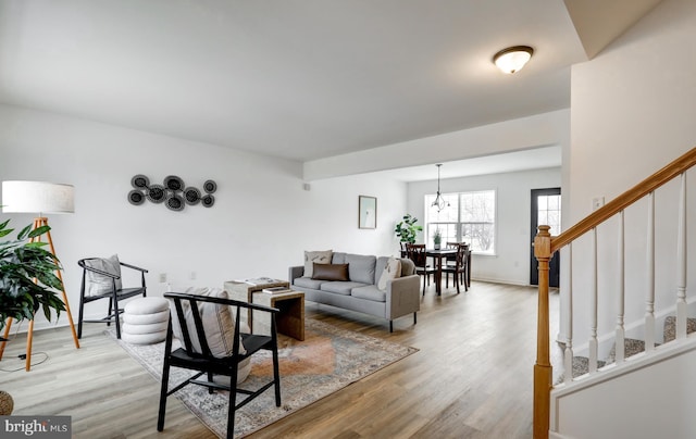 living area featuring stairway, light wood-style flooring, and baseboards