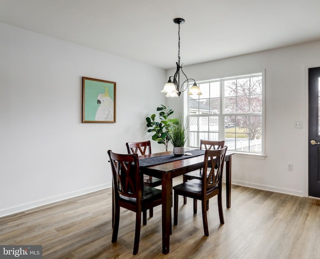 dining space featuring a notable chandelier, baseboards, and wood finished floors