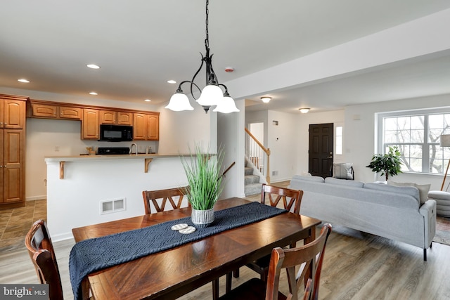 dining room featuring visible vents, recessed lighting, light wood finished floors, baseboards, and stairs