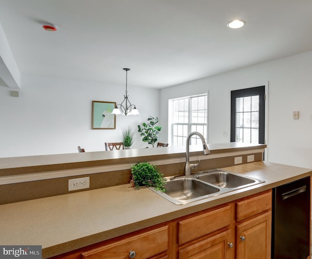 kitchen with brown cabinetry, a sink, light countertops, pendant lighting, and dishwasher