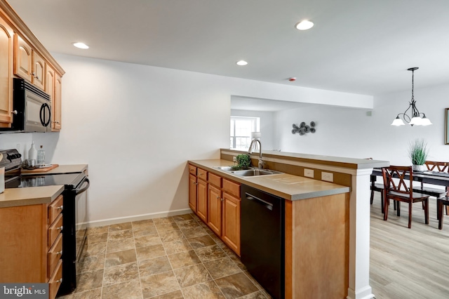 kitchen featuring a peninsula, black appliances, light countertops, and a sink